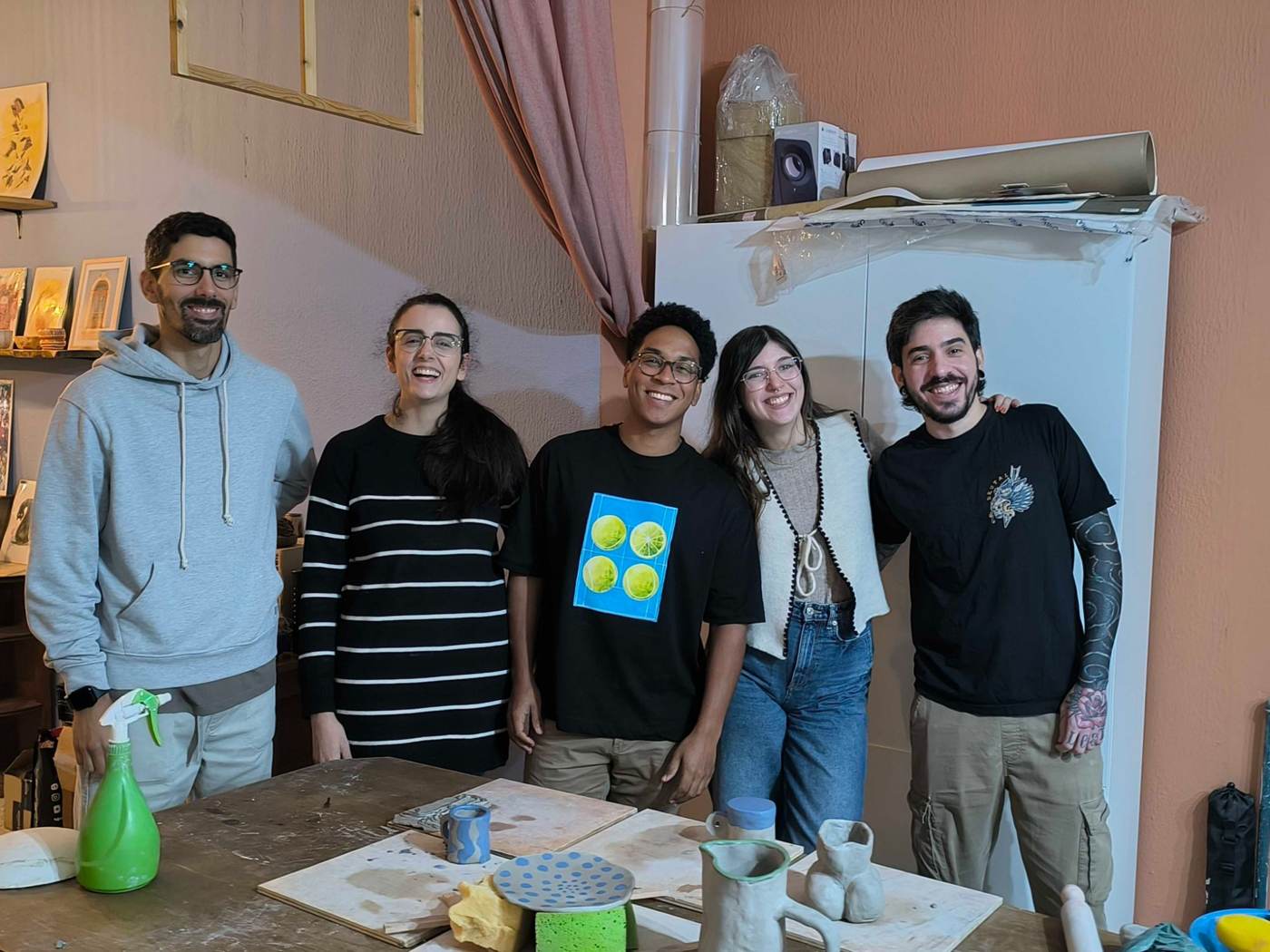 The team smiling behind a table of clay pots at the 2026 pottery workshop